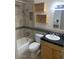 A full bathroom with a tiled shower and tub, wooden vanity, and dark countertop and accent tile at 207 E Papago Dr, Tempe, AZ 85288