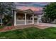 Inviting single-story home with a charming front porch and lush green lawn at dusk at 20866 W Hamilton St, Buckeye, AZ 85396