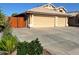 Spacious driveway leading to a three-car garage, complemented by desert landscaping and a fenced yard at 2434 S Colleen --, Mesa, AZ 85210