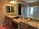 Bathroom featuring dual sinks, granite counters, a large mirror, and glass door shower at 2585 E Carob Dr, Gilbert, AZ 85298