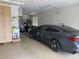 Well-lit garage featuring a sleek gray car, storage cabinets, and essential utility fixtures at 2585 E Carob Dr, Gilbert, AZ 85298