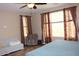 Bright main bedroom featuring a ceiling fan, natural light, and a comfortable sitting area at 2585 E Carob Dr, Gilbert, AZ 85298
