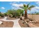 Well-manicured backyard with winding pathways, mature landscaping, desert features, and a stone waterfall at 3700 N 149Th Ln, Goodyear, AZ 85395