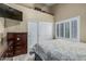 Neutral bedroom features a bed, dresser, and large window with shutters, complemented by a mounted TV at 11511 E Chestnut Ct, Chandler, AZ 85249