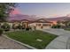 Charming home with three-car garage, desert landscaping, and warm exterior lighting at sunset at 11511 E Chestnut Ct, Chandler, AZ 85249