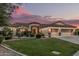 Charming home with three-car garage, desert landscaping, and warm exterior lighting at sunset at 11511 E Chestnut Ct, Chandler, AZ 85249