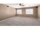 Spacious bedroom with neutral carpet, a ceiling fan, and two windows with blinds at 12430 W Scotts Dr, El Mirage, AZ 85335