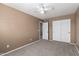 Bedroom with neutral carpeting and a ceiling fan with views of the closet and doorway at 12430 W Scotts Dr, El Mirage, AZ 85335