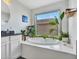Bathroom featuring a soaking tub with a view and white cabinets with dark countertops at 16322 N 171St Dr, Surprise, AZ 85388