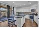 A kitchen island with barstool seating features stainless steel appliances and an adjacent sliding glass door at 16322 N 171St Dr, Surprise, AZ 85388