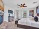 This main bedroom features a stone fireplace, ceiling fan, mounted TV and stylish decor at 16322 N 171St Dr, Surprise, AZ 85388