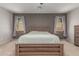 Well-lit main bedroom with a wooden bed frame, two windows, carpet and neutral tones for relaxation at 17219 W Gibson Ln, Goodyear, AZ 85338