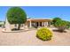 Attractive home exterior with well-maintained landscaping, gravel, mature trees and covered patio at 17371 N Natura Trl, Surprise, AZ 85374
