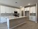 Modern kitchen featuring white cabinets, an island with quartz countertops, and stainless steel appliances at 17482 W Fulton St, Goodyear, AZ 85338