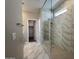 Elegant bathroom featuring a glass-enclosed walk-in shower with tiled walls and floors, and a walk-in closet at 17488 W Fulton St, Goodyear, AZ 85338