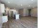Open-concept kitchen with white cabinetry, stainless steel appliances, and a center island, seamlessly flowing into the living area at 17488 W Fulton St, Goodyear, AZ 85338
