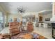 Spacious living room featuring a ceiling fan, travertine floors, and access to the backyard at 19541 N Rim Dr, Surprise, AZ 85374