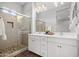 Bright bathroom featuring double sinks, white cabinetry, and a glass-enclosed shower at 20607 W Point Ridge Rd, Buckeye, AZ 85396