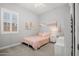 This bedroom has a window with white panes and a small bed with a pink comforter at 20607 W Point Ridge Rd, Buckeye, AZ 85396
