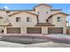 Apartment complex with multiple garages and a tan stucco exterior under a clear blue sky at 2315 N 52Nd St # 102, Phoenix, AZ 85008