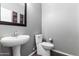 Bathroom showcasing a sleek pedestal sink, modern toilet, and elegant mirror at 23955 W La Salle St, Buckeye, AZ 85326