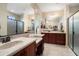 Primary bathroom featuring dual sinks, dark wood cabinetry, and a glass shower at 26725 W Marco Polo Rd, Buckeye, AZ 85396