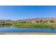 Scenic golf course view with lush green grass, a serene lake, and picturesque mountain backdrop at 3109 N Black Rock Rd, Buckeye, AZ 85396