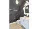 Stylish powder room featuring a white vanity, unique mirror, and modern fixtures against a dark wall at 3136 E Cheryl Dr, Phoenix, AZ 85028