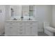 Bright bathroom features a double sink vanity, lighted mirror, and modern toilet at 43481 W Carefree Pl, Maricopa, AZ 85138