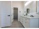 Modern bathroom features a double sink vanity, lighted mirror, and walk-in closet access at 43481 W Carefree Pl, Maricopa, AZ 85138