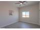Neutral bedroom features wood-look tile, ceiling fan, window and white horse art at 43481 W Carefree Pl, Maricopa, AZ 85138