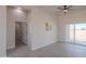 Well-lit living room with an adjacent doorway, light wood floors, and a large sliding glass door at 43481 W Carefree Pl, Maricopa, AZ 85138