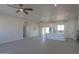 Open-concept living room with light wood floors, ceiling fans, and a modern kitchen with white cabinets at 43481 W Carefree Pl, Maricopa, AZ 85138