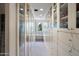 Bright walk-in closet features custom cabinetry, drawers, carpet, arched window with natural light, and glass doors at 6997 E Paradise Ranch Rd, Paradise Valley, AZ 85253