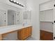 Bright bathroom featuring a sink with wood cabinets, a large mirror, and walk-in closet access at 8745 W Windsor Dr, Peoria, AZ 85381