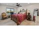 Bedroom with a ceiling fan, view of exterior, desk, mirror, and neutral toned walls and floors at 11119 W Mountain View Rd, Sun City, AZ 85351