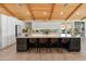 Island kitchen with waterfall countertop, seating, bright white cabinets, and tile backsplash with wood ceiling at 11119 W Mountain View Rd, Sun City, AZ 85351