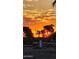 Sunset view showcasing palm trees and a vibrant, orange-hued sky over a suburban street at 11119 W Mountain View Rd, Sun City, AZ 85351