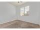 This bedroom has neutral carpet, blank walls, and a window that provides natural light and a view of the outdoors at 16215 W Durango St, Goodyear, AZ 85338