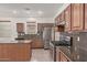 Traditional kitchen with stainless steel appliances, granite countertops, ample wood cabinetry, and tile flooring at 16215 W Durango St, Goodyear, AZ 85338