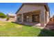Manicured backyard with a covered patio, lush green lawn, and secure perimeter fencing at 16768 W Nottingham Way, Surprise, AZ 85374