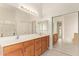 Bathroom featuring a double sink vanity with wood cabinets, ample counter space, and a large mirror at 16768 W Nottingham Way, Surprise, AZ 85374