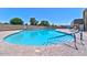 Bright blue community pool surrounded by lush trees, seating, and accessibility handrails at 6705 E Des Moines St, Mesa, AZ 85205