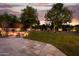 Expansive backyard with lush green lawn and stone patio featuring a cozy fire pit and seating area, perfect for outdoor relaxation at 10380 E Cholla St, Scottsdale, AZ 85260