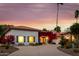 Desert home at dusk, featuring a circular driveway, desert landscaping, and bright bougainvillea at 10380 E Cholla St, Scottsdale, AZ 85260