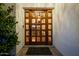 A warm wooden front door featuring glass insets and decorative foliage creating an inviting entrance at 10380 E Cholla St, Scottsdale, AZ 85260