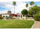 Inviting home featuring a well-manicured lawn, mature palm trees, and vibrant bougainvillea enhancing its curb appeal at 10380 E Cholla St, Scottsdale, AZ 85260