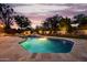 Well-lit swimming pool surrounded by lush landscaping, offering a tranquil retreat for relaxation and recreation at 10380 E Cholla St, Scottsdale, AZ 85260