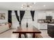 Inviting dining area featuring modern lighting, a large wooden table, and an open layout connecting to the living room and kitchen at 14114 W Surrey Dr, Surprise, AZ 85379