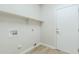 Bright laundry room featuring light-colored walls, flooring, a shelf, and convenient utility hookups and adjacent white door at 1584 E Harrison E St, Chandler, AZ 85225